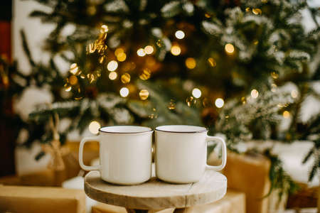New year 2022, christmas. House room decorated for the holidays. Two cups of tea or coffee on the background of the Christmas tree. Christmas drinks. Warmth and comfortの写真素材