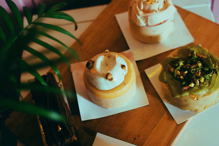 A variety of desserts from a bakery on a plank on a pink background. Diet and sweets. Many delicious...