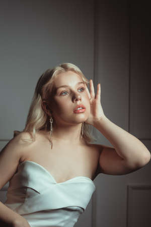 Portrait of a bride, a woman in a white dress with a beautiful pink make-up. Long earrings as a decoration for a wedding, jewelry for the bride.の写真素材