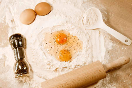 Cooking homemade dough, flour and eggs on the table. Rolling pin and pepper on eggs. Cooking at home, recipes, dietの写真素材