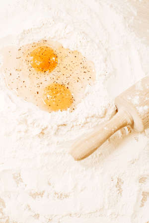 Cooking homemade dough, flour and eggs on the table. Rolling pin and pepper on eggs. Cooking at home, recipes, dietの写真素材