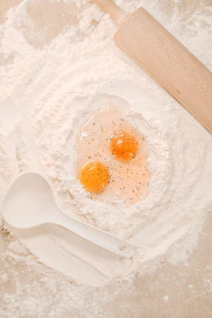 Cooking homemade dough, flour and eggs on the table. Rolling pin and pepper on eggs. Cooking at home, recipes, dietの写真素材