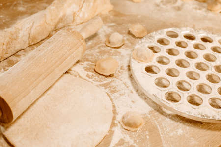 Making homemade dumpling dough. The rolling pin rolls out dough, flour and a mold for dumplings or ravioli. Home cooking food. National cuisine.の写真素材