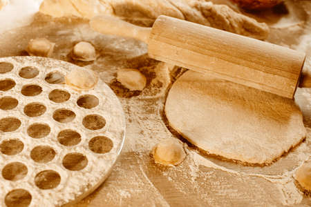Making homemade dumpling dough. The rolling pin rolls out dough, flour and a mold for dumplings or ravioli. Home cooking food. National cuisine.の写真素材