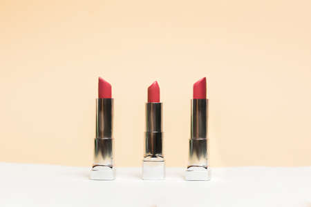 Lipstick different colors, shades options. Cosmetics on nude background. Beautiful examples of lipsticks, pink and red.の写真素材