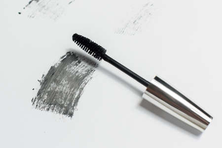Mascara lies on a white background, and leaves a black mark showing how the brush works. Cosmetics and make-up personal care.の写真素材