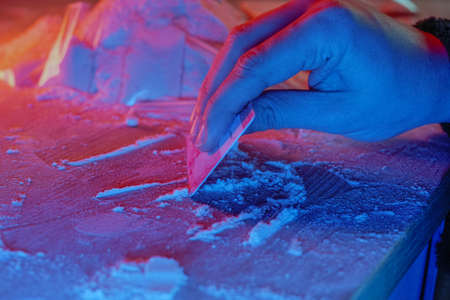 Drugs, drug dealer house. Cocaine packaged in sachets, scales: tablets and syringes in neon light. Illegal, entry.の写真素材