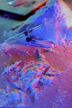 Drugs, drug dealer house. Cocaine packaged in sachets, scales: tablets and syringes in neon light. Illegal, entry.の写真素材