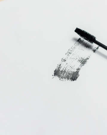 Mascara lies on a white background, and leaves a black mark showing how the brush works. Cosmetics and make-up personal care.の写真素材