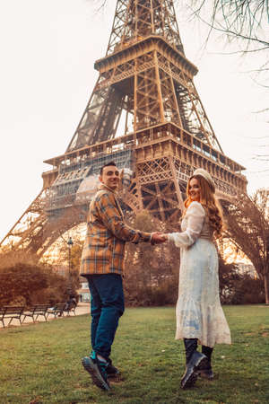 A couple in Paris with the Eiffel Tower in the background. Romantic trip, honeymoon in Europe. France city of love. Follow me. Love.の写真素材