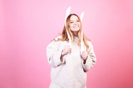 Beautiful girl in rabbit ears on a pink background laugh, Easter holidays. The woman smiles. Looks to the side, space for text, funの写真素材