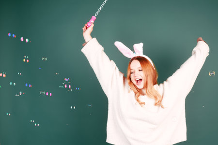 The girl on the Easter holidays blows bubbles on a green background. A beautiful girl rejoices and...