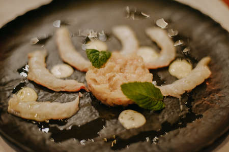 Photo of food in an expensive restaurant during dinner. Shrimps on a black plate.の写真素材