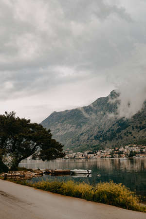 Beautiful photo of the city and mountains in the clouds, nature and recreation, boats on the water in the eveningの写真素材