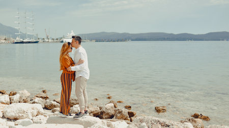 A couple walks along the beach against the backdrop of the sea and mountains. Travel of lovers. Love and honeymoon. Man kissing a girl.の写真素材