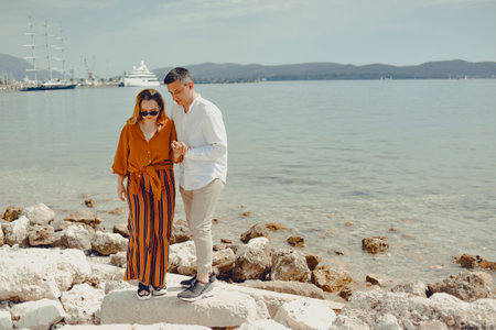A couple walks along the beach against the backdrop of the sea and mountains. Travel of lovers. Love and honeymoonの写真素材