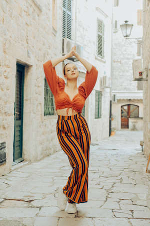 A very beautiful woman poses on the streets of an old city in Europe while traveling. Leisure and vacation in Europe. Beautiful girl with stylingの写真素材