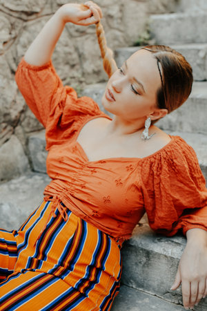 Gorgeous brunette posing lying on the stairs. Jewelry silver earrings, professional makeup, yellow suit. elegant touristの写真素材