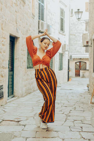 A very beautiful woman poses on the streets of an old city in Europe while traveling. Leisure and vacation in Europe. Beautiful girl with stylingの写真素材