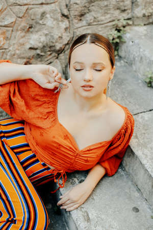 Gorgeous brunette posing lying on the stairs. Jewelry silver earrings, professional makeup, yellow suit. elegant touristの写真素材