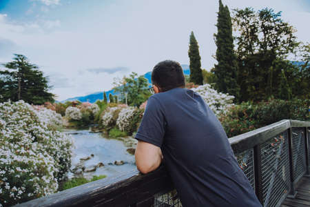 A man on the shore of the lake Riva Del Garda and against the backdrop of the mountains makes looks at the stream. Tourist in Italy. beauty of natureの写真素材