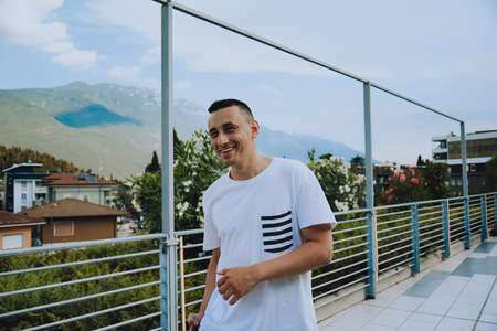 A man against the backdrop of mountains and flowers on a sunny day tourist smiles and rests in Italy. hipster photoの写真素材