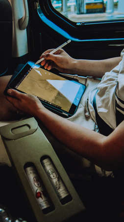 Italy. Venice. 09/07/2022. A man draws on a tablet on the road in the car. The guy makes a logo on the iPad.の写真素材