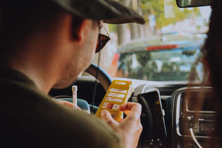 A man driving a car blows into a disposable . Drunk man driving, the guy checks how many ppm he has. Self checks alcohol levelの写真素材