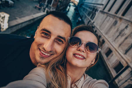 A couple takes a selfie in front of the Grand Canal in Venice. Tourists on the road