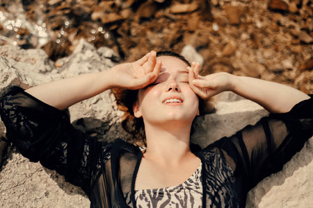 A woman lies on the beach near the water in sunny weather and smiles. summer photo