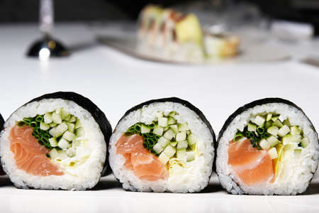 Sushi on a white background in sesame seeds with avocado and nigiri. Futomaki with salmon and cucumber. Foodの写真素材
