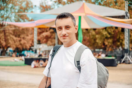 The man at the festival. A tourist with a backpack looks at the camera and smiles.の写真素材