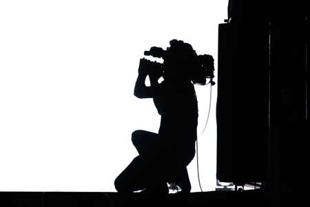 Videographer profession. Silhouette of a man with a camera who shoots a video on a white backgroundの写真素材