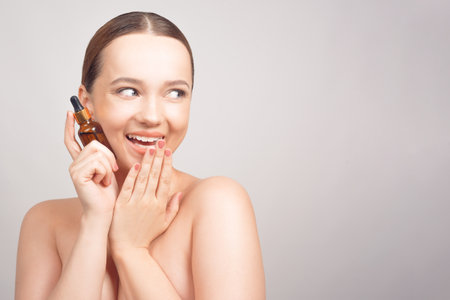 Girl on a white background skin care, oil, serum with a pipette smileの写真素材