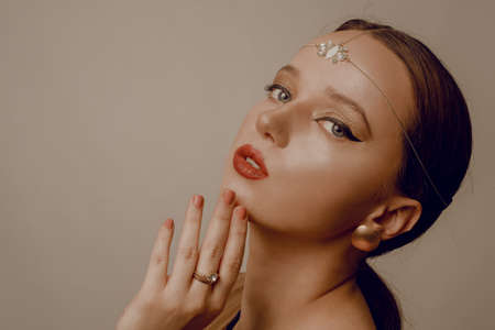 Girl with Dubai make-up. Perfect arrows, red lips, gold jewelry, jewelry on the forehead. Indian girl, indian jewelryの写真素材