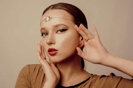 Girl with Dubai make-up. Perfect arrows, red lips, gold jewelry, jewelry on the forehead. Indian girl, indian jewelryの写真素材
