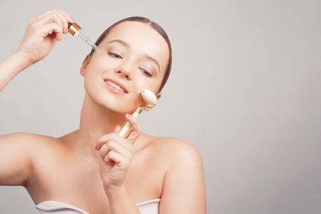 Girl on a white background skin care, oil, serum with a pipette on her faceの写真素材