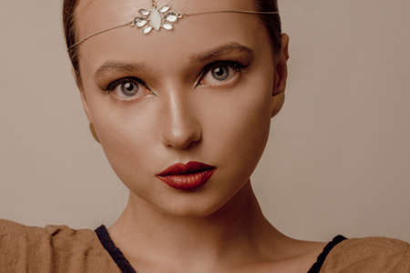 Girl with Dubai make-up. Perfect arrows, red lips, gold jewelry, jewelry on the forehead. Indian girl, indian jewelryの写真素材