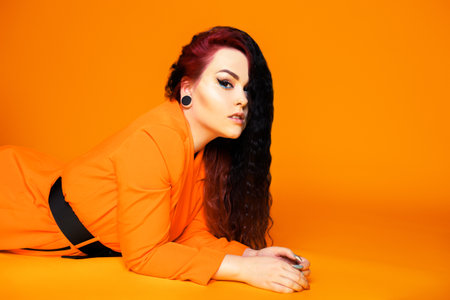 A beautiful girl with red hair and an orange jacket. Woman with beautiful make-up and pink hair beauty salonの写真素材