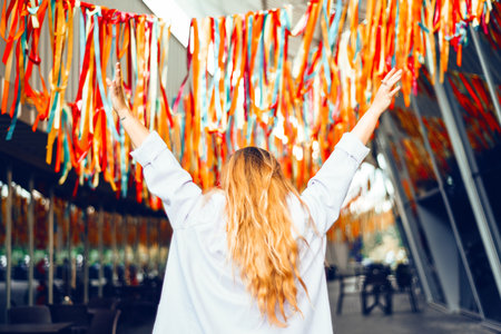 Portrait of a beautiful girl at the festival. A woman dances and smiles in a dress and glasses on a holiday against the background of confetti.の写真素材