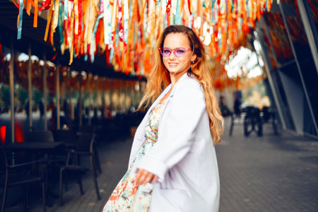 Portrait of a beautiful girl at the festival. A woman dances and smiles in a dress and glasses on a holiday against the background of confetti.の写真素材