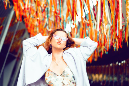 Portrait of a beautiful girl at the festival. A woman dances and smiles in a dress and glasses on a holiday against the background of confetti.の写真素材