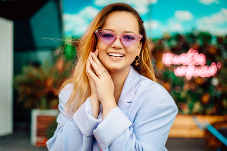 A girl in a dress, jacket and purple sunglasses poses at the festival portrait. Smile and joy, emotions.の写真素材