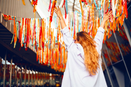 Portrait of a beautiful girl at the festival. A woman dances and smiles in a dress and glasses on a holiday against the background of confetti.の写真素材
