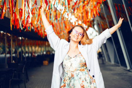 Portrait of a beautiful girl at the festival. A woman dances and smiles in a dress and glasses on a holiday against the background of confetti.の写真素材
