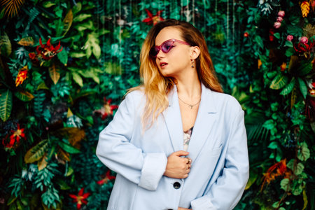 A girl in a dress, jacket and purple sunglasses poses at the festival portrait. Smile and joy, emotions against the backdrop of greenery and a waterfall. fashion outfitの写真素材