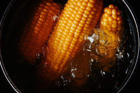 Orange juicy corn is boiled in water with salt. Corn in boiling water in a saucepan. Healthy food at homeの写真素材