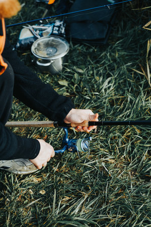 Male hands hold a fishing rod against the background of grass. Fishingの写真素材