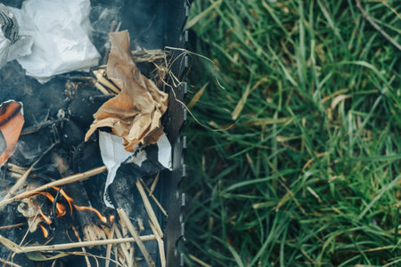 The fire on the grill stands on the grass. They make fire with paper and branches, natural fuel.の写真素材