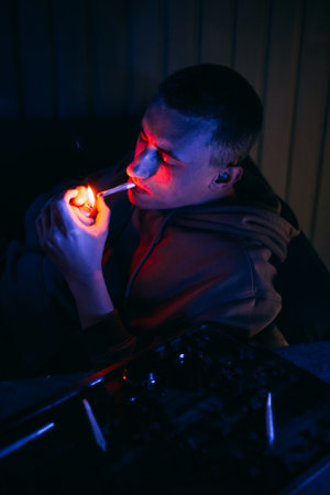 Portrait of a man in neon who smokes a joint. Guy smokes joint, marijuana, drugs cbd and thcの写真素材